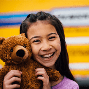 Fille avec un ours en peluche devant un camion de location